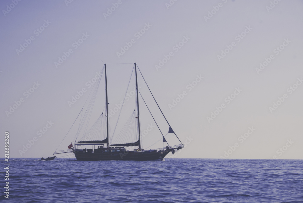 Vintage background of sailing boat on plain ocean and sky