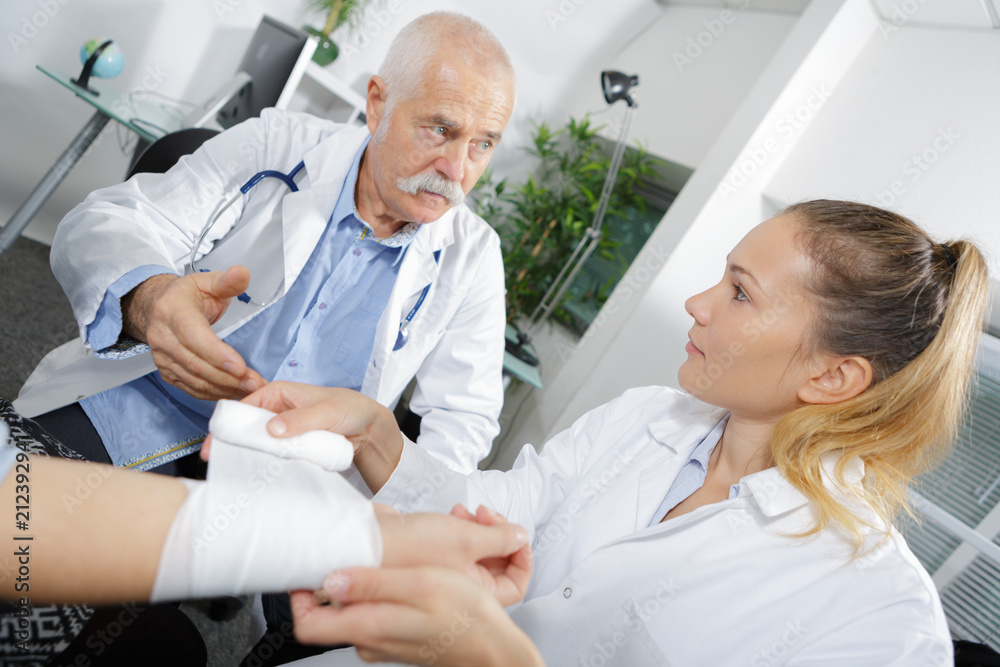 senior doctor and assistant bandaging one injured arm senior doctor and assistant bandaging one injured arm