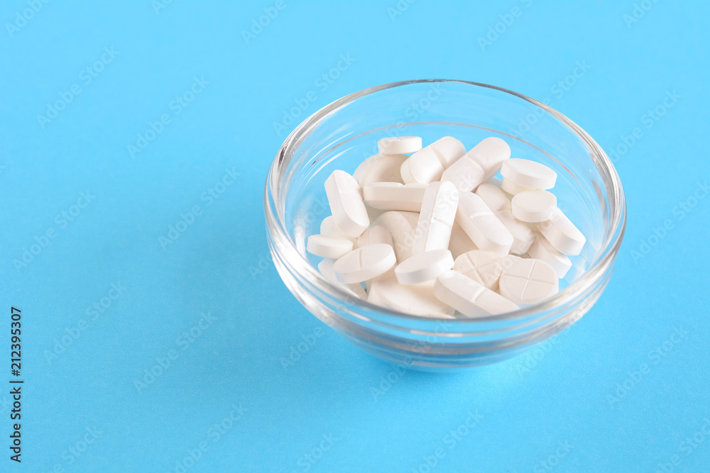Pile of white pills on light blue background Pile of white pills on light blue background
