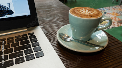Coffee cup with laptop on table in coffee shop.