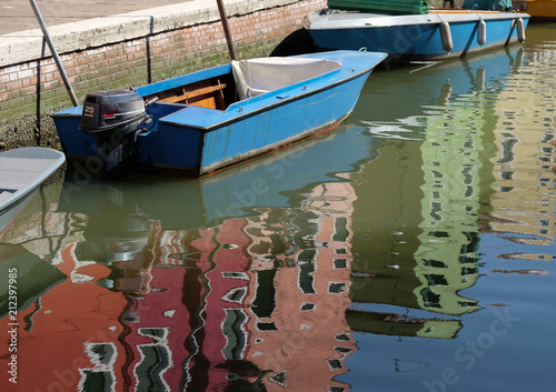 Boats and colorful buildings reflected in the canal of Burano