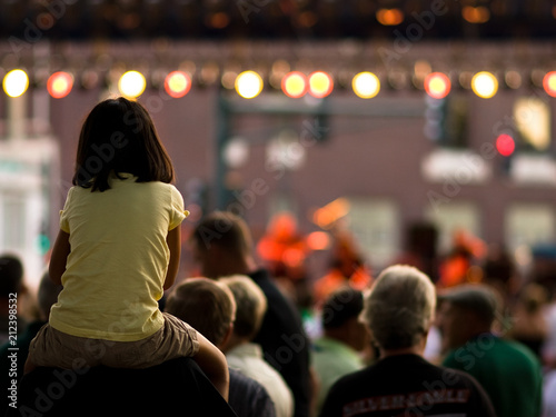 Young girl on her dad's shoulders at a concert