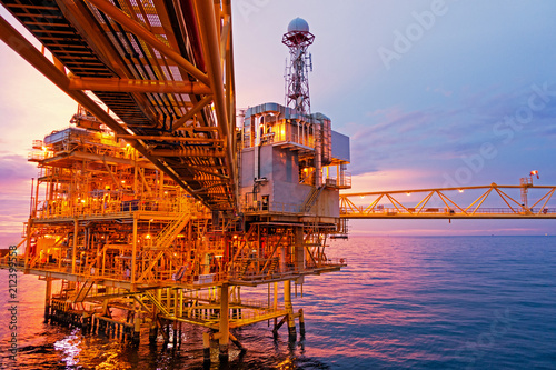 Offshore construction platform for exploration and production oil and gas with bridge in evening time for power energy of the world concept
