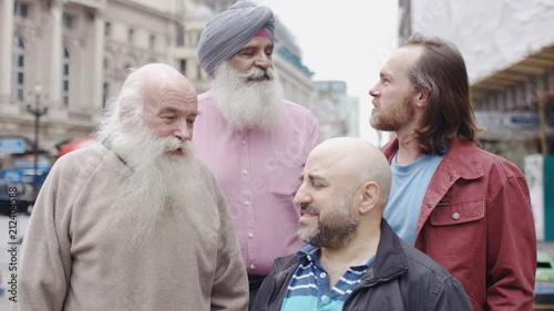 Group of diverse bearded men talking in the street before looking to camera, in slow motion