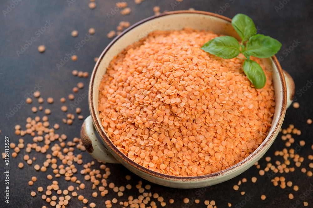 Uncooked red lentils in a bowl, studio shot on a brown metal background, selective focus Uncooked red lentils in a bowl, studio shot on a brown metal background, selective focus