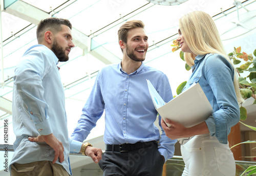 Young modern colleagues in smart casual wear having a brainstorm meeting while standing in the creative office. photo