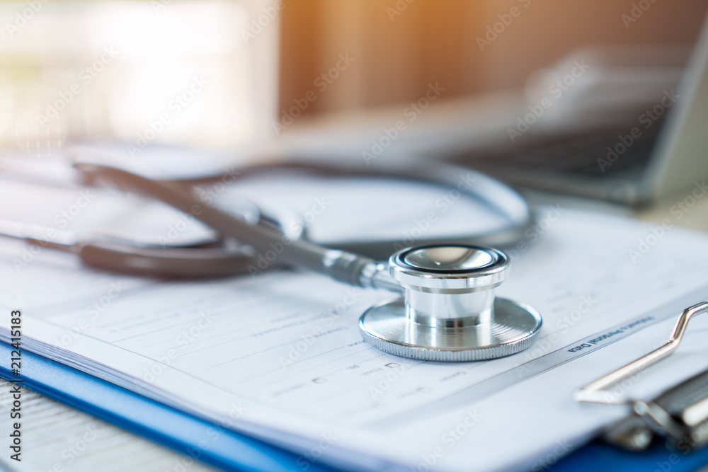 Stethoscope on prescription clipboard record on hospital office with Laptop computer at doctor work office in hospital or clinic with light flare, Concept of Health Care and Medical. Selective focus. Stethoscope on prescription clipboard record on hospital office with Laptop computer at doctor work office in hospital or clinic with light flare, Concept of Health Care and Medical. Selective focus.