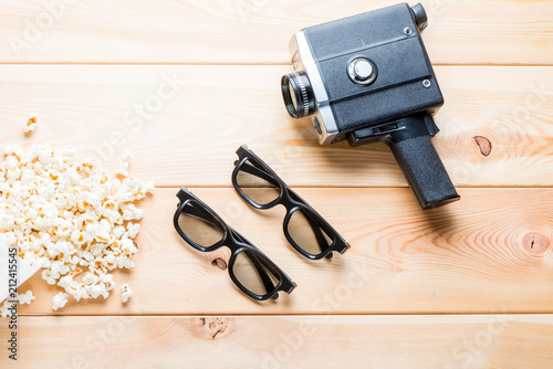 salted popcorn, 3d glasses for two spectators and retro camera on wooden boards top view