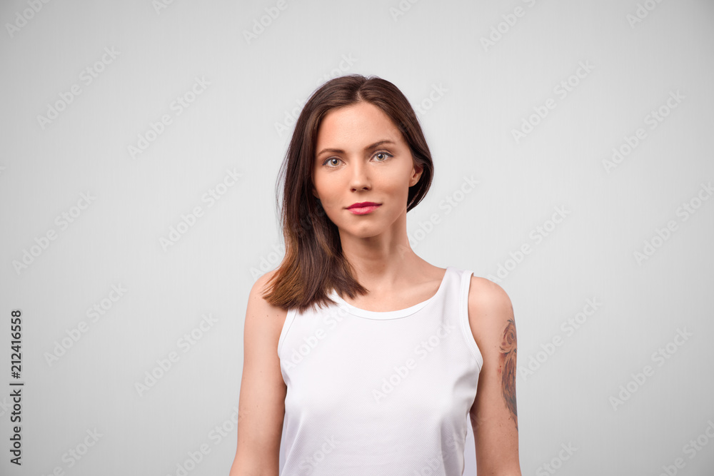 Beautiful young woman portrait. Studio shot, isolated on gray background. Portrait of young beautiful cute cheerful girl smiling looking at camera Beautiful young woman portrait. Studio shot, isolated on gray background. Portrait of young beautiful cute cheerful girl smiling looking at camera