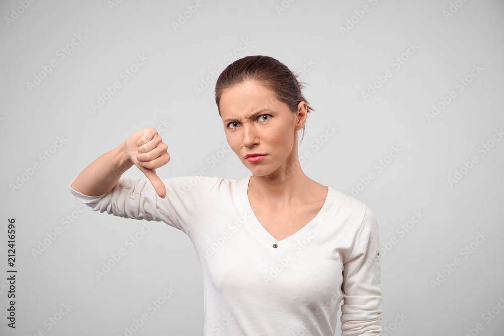 Thumbs down woman unhappy and negative giving disapproval hand sign. Caucasian young businesswoman. Teenage girl showing thumb down. Looking at camera. Front view. White background Thumbs down woman unhappy and negative giving disapproval hand sign. Caucasian young businesswoman. Teenage girl showing thumb down. Looking at camera. Front view. White background