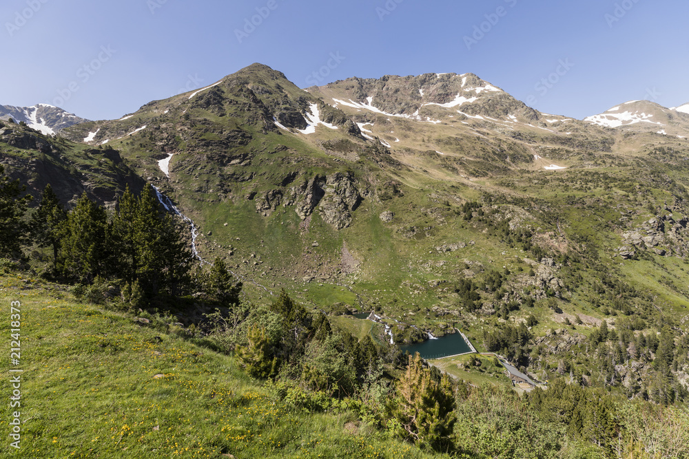 High alpine landscape with snow fields and lakes in the region Ordino Arcalis in the Pyrenees of Andorra