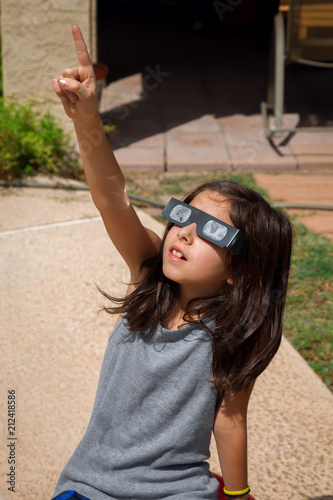 Young Girl Pointing To the Sky While Wearing Eclipse Glasses On a Bright Day