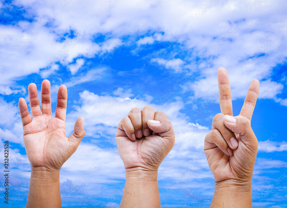 Rock Paper and Scissors on sky background. Hand young man are playing rock paper scissors. Rock Paper and Scissors on sky background. Hand young man are playing rock paper scissors.