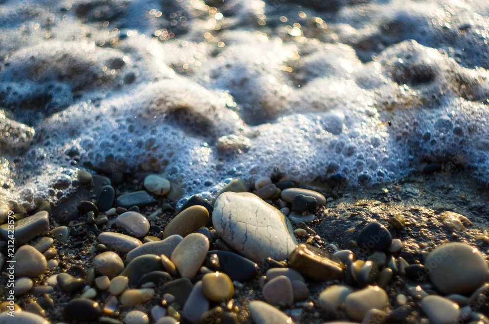 pebble stones on the sea beach, the rolling waves of the sea with foam pebble stones on the sea beach, the rolling waves of the sea with foam
