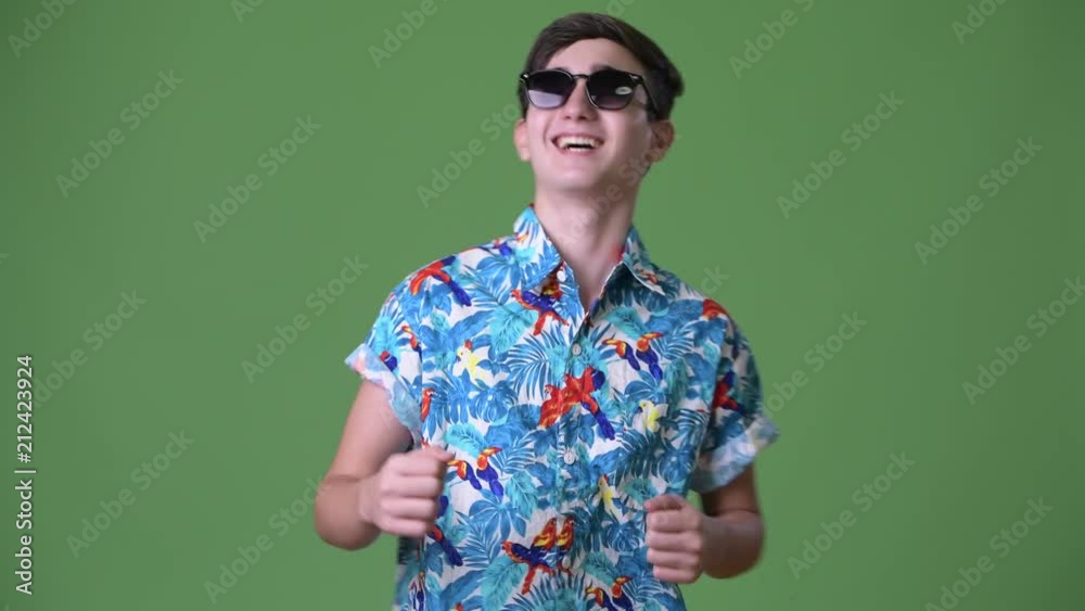Young handsome Iranian teenage boy ready for vacation against green background Young handsome Iranian teenage boy ready for vacation against green background