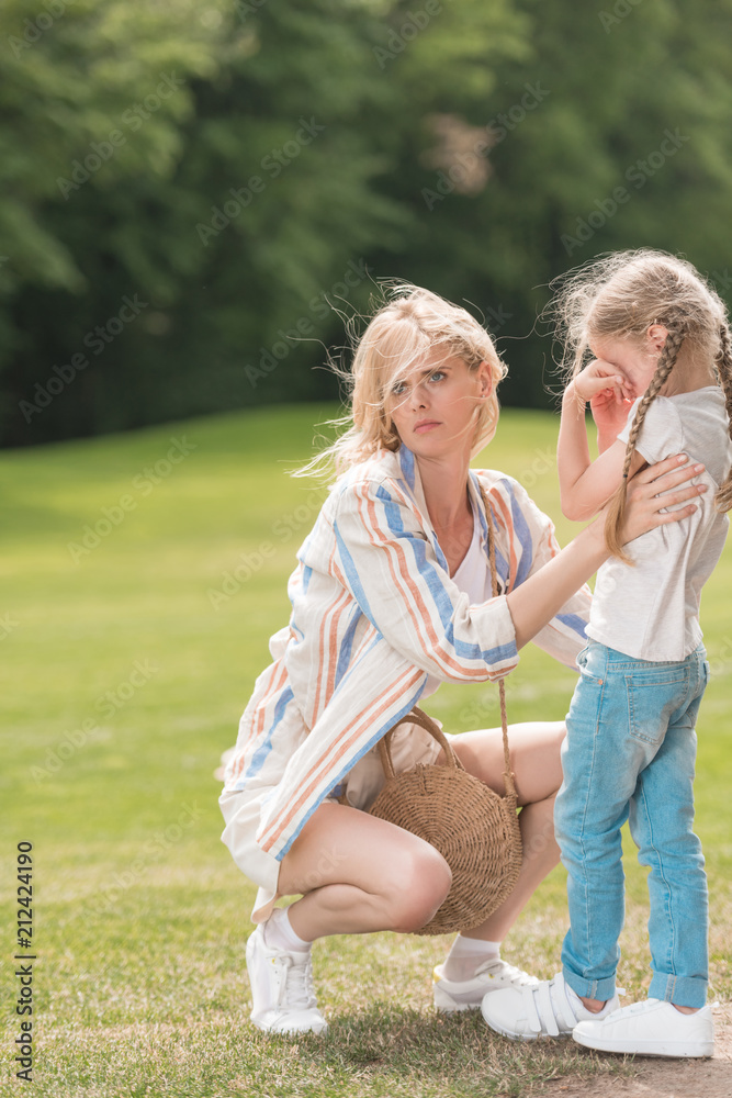Fototapeta premium young mother hugging little daughter crying in park