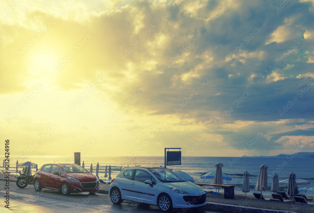 cars and motorcycle on the beach near the beach and umbrellas on the background of the sunset clouds and the sun, sunset, toning
