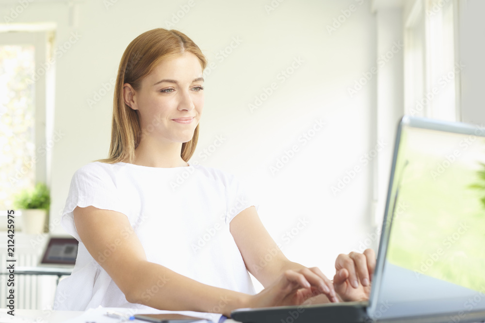 Young professional woman using laptop while working at home office Young professional woman using laptop while working at home office