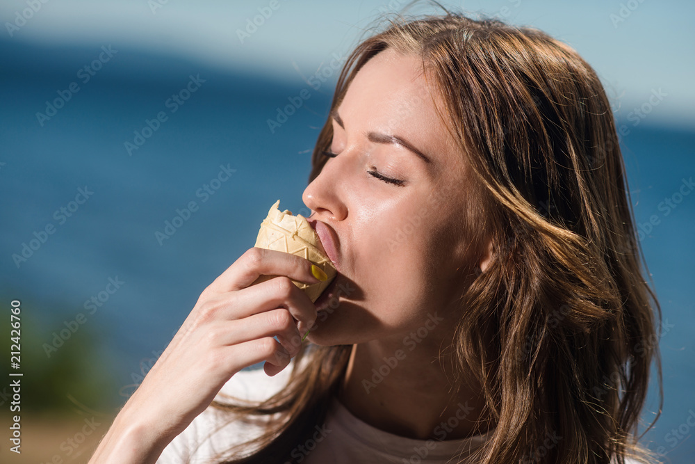 Young girl eating ice cream outdoors in summer, in heat