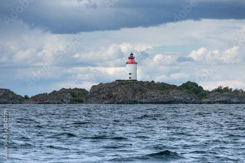 Scandinavian coastal landscape with lighthouse. Dramatic sky