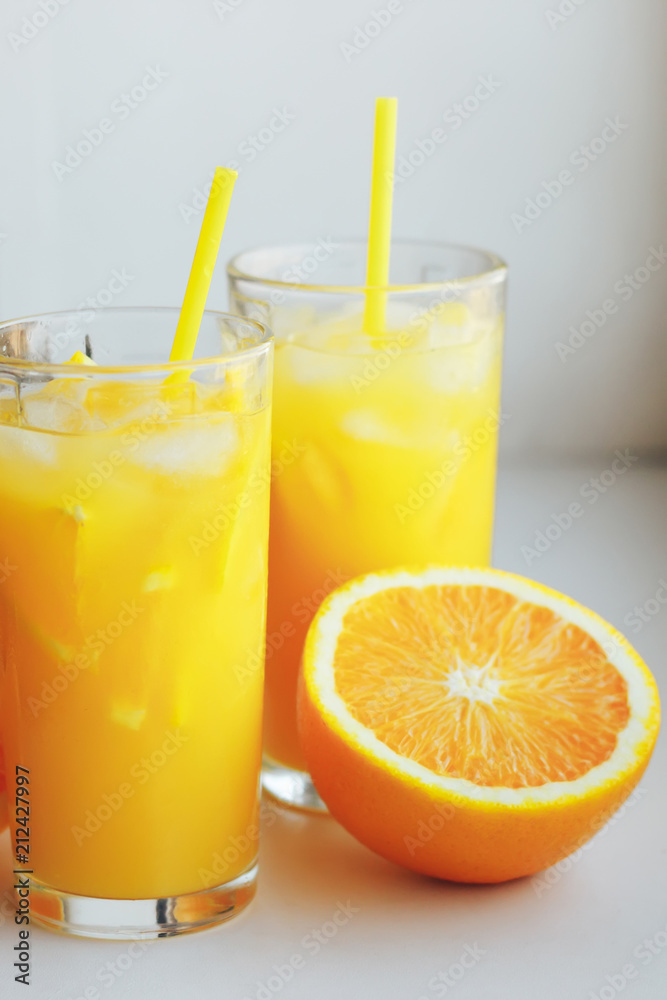 Glasses of fresh orange juice with ice and orange slices on a white background. Glasses of fresh orange juice with ice and orange slices on a white background.