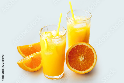 Glasses of fresh orange juice with ice and orange slices on a white background.