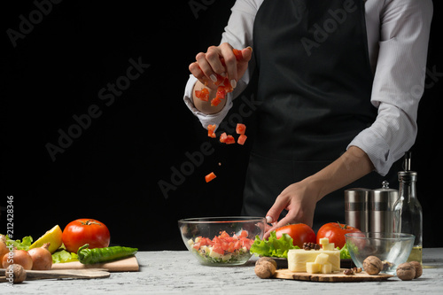 The chef prepares a salad  frozen tomatoes on a dark background with an empty space for writing