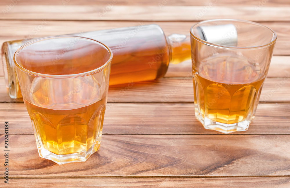Two glasses of whisky with bottle of whiskey on wooden background. Two glasses of whisky with bottle of whiskey on wooden background.