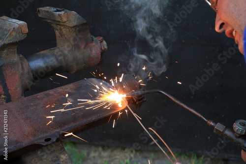 The man is a gas master and an electric welder. When the welding machine is in operation, bright sparks fly. A man welds metal parts.
