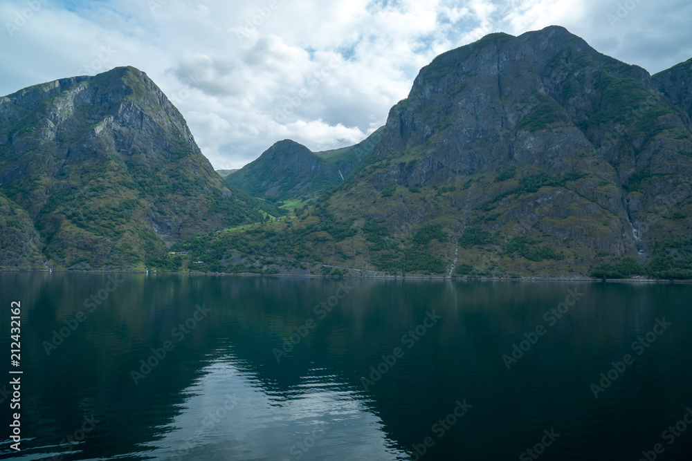 massive geiranger fjord in norway seen from a cruise ship with light shining through the clouds