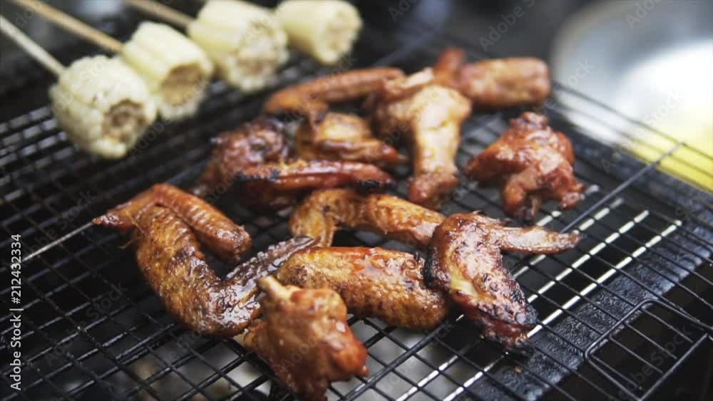 Tasty Chiken wings meat grilled on barbeque with corn on sticks outside in sunny day.