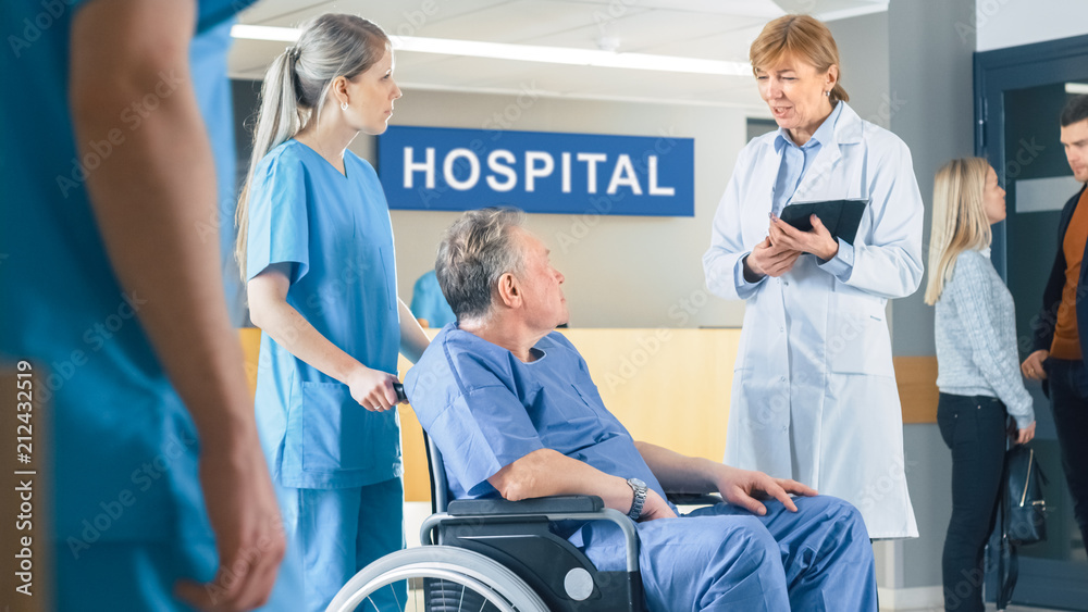 In the Hospital Lobby, Nurse Pushes Elderly Patient in the Wheelchair, Doctor Talks to Them while Using Tablet Computer. Clean, New Hospital with Professional Medical Personnel. In the Hospital Lobby, Nurse Pushes Elderly Patient in the Wheelchair, Doctor Talks to Them while Using Tablet Computer. Clean, New Hospital with Professional Medical Personnel.