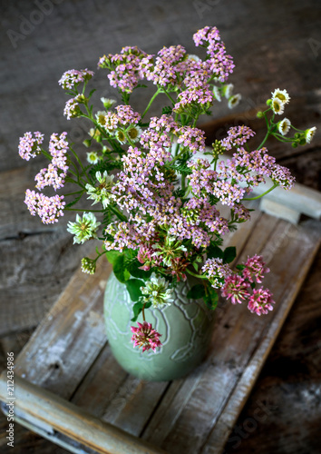 A bouquet in a vase of summer wild flowers on a wooden table, in rustic style.