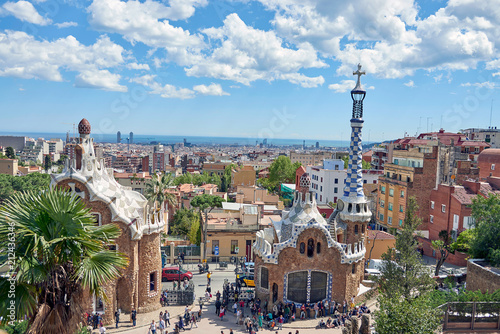 Barcelona, Spain. April 19, 2017: View of the entrance of Park Guell, the work of the architect Gaudi full of tourists with the guard house and the bookshop and panoramic view of Barcelona behind photo