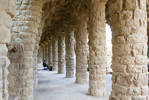 Barcelona, Spain. April 19, 2017: Street musician in the inner part made of arches with stone columns of a Guell Park footbridge, made by the Spanish architect Gaudi photo