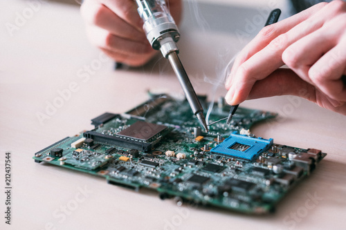electronic renovation in repair shop. engineer soldering computer motherboard photo