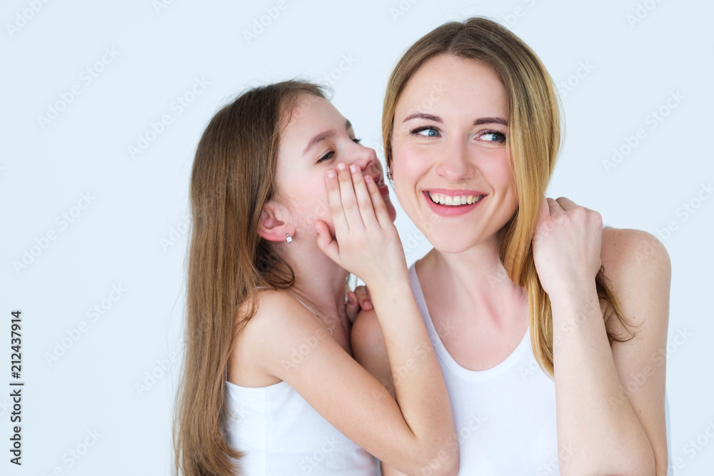 good parenting and loving family relationships. daughter whispering a secret into her mothers ear. good parenting and loving family relationships. daughter whispering a secret into her mothers ear.