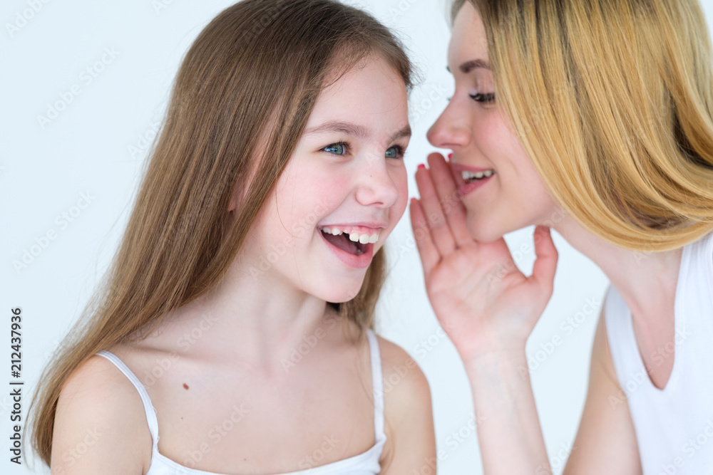 mom and kid communication. mother sharing a secret. woman whispering something into her daughter ear. mom and kid communication. mother sharing a secret. woman whispering something into her daughter ear.