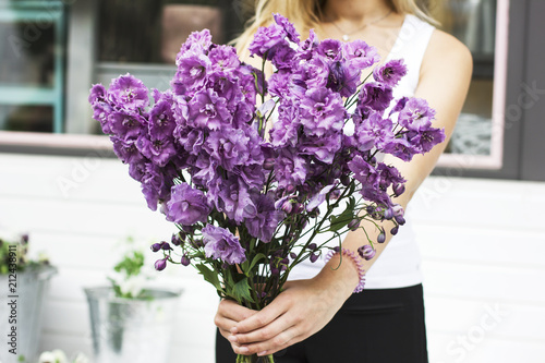 Bouquet of purple lilac delphinium in women's hands on the street