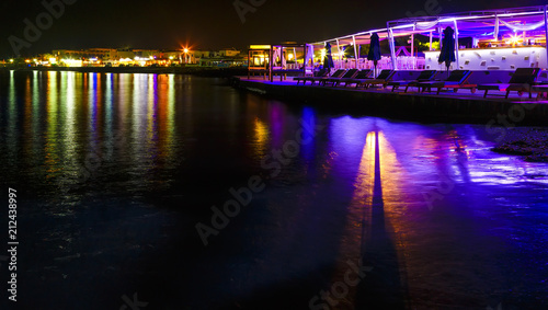 night cafe and reflection of lights in the water on the island of Crete, Greece, Europe