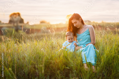 mother with little daughter sitting on meadow