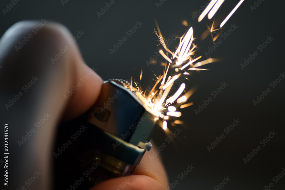 Lighters with flame sparking on dark background. Selective focus and shallow depth of field. - obrazy, fototapety, plakaty 