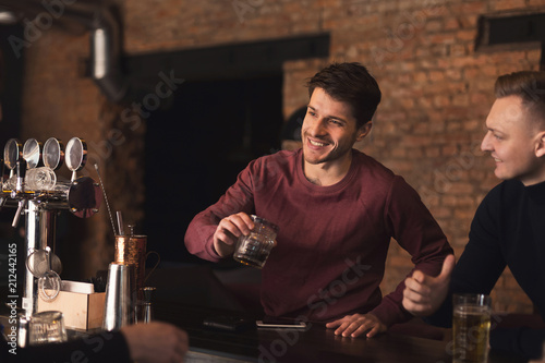 Cheerful friends in bar communicating with bartender