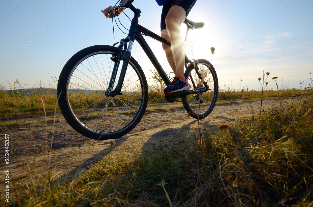 Male cyclist driving by rural dirt road outdoors. Low angle view Male cyclist driving by rural dirt road outdoors. Low angle view