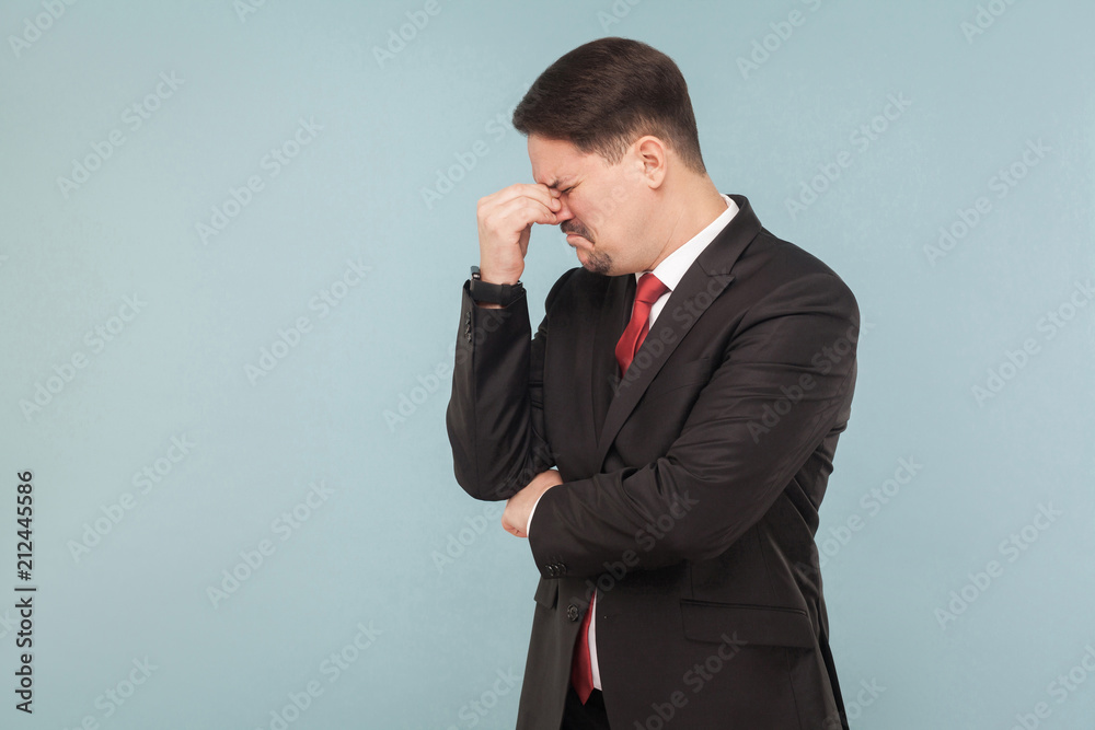 Looser businessman, crying, and hope. Need a new job and many money. indoor studio shot. isolated on light blue background. handsome businessman with black suit, red tie and mustache. side view. Looser businessman, crying, and hope. Need a new job and many money. indoor studio shot. isolated on light blue background. handsome businessman with black suit, red tie and mustache. side view.