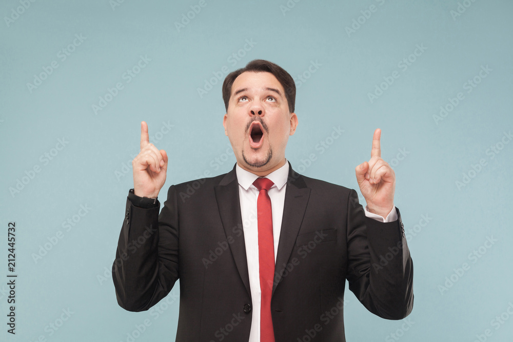 Emotional man showing finger up. Сan not be this is a discount!. indoor studio shot. isolated on light blue background. handsome businessman with black suit, red tie and mustache looking up. Emotional man showing finger up. Сan not be this is a discount!. indoor studio shot. isolated on light blue background. handsome businessman with black suit, red tie and mustache looking up.