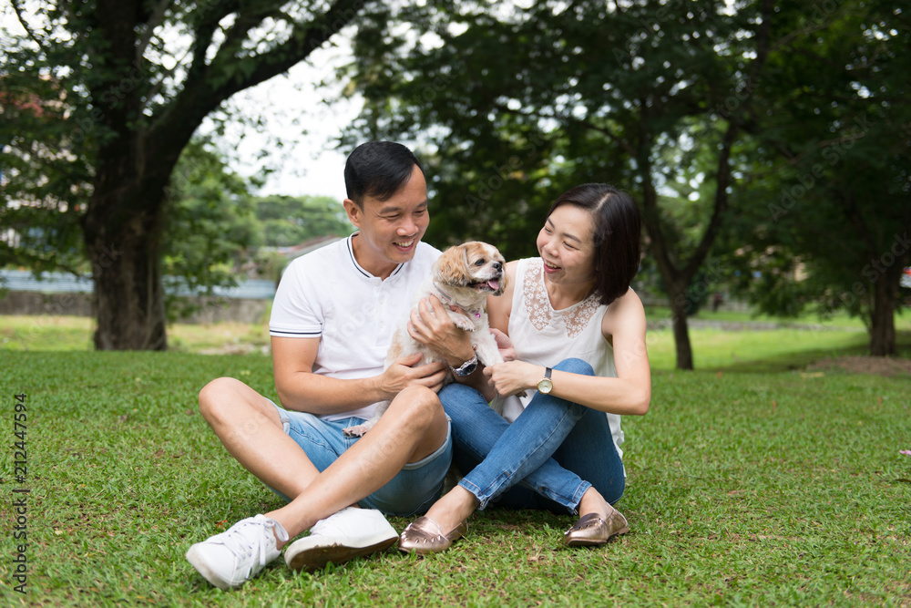 Lovely asian couple with their pet shih tzu puppy at outdoor park
