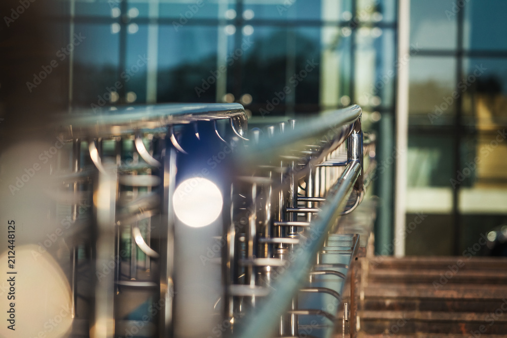 metal clean glossy handrails of the passage of the modern glass building outdoors. construction illuminated by sunlight