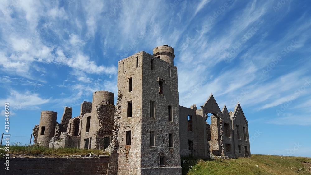 Ruins of castle against dramtic sky with streaky white clouds