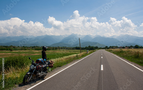 Young woman motorcyclist traveler looks at the mountains. Transfagarasan Romania